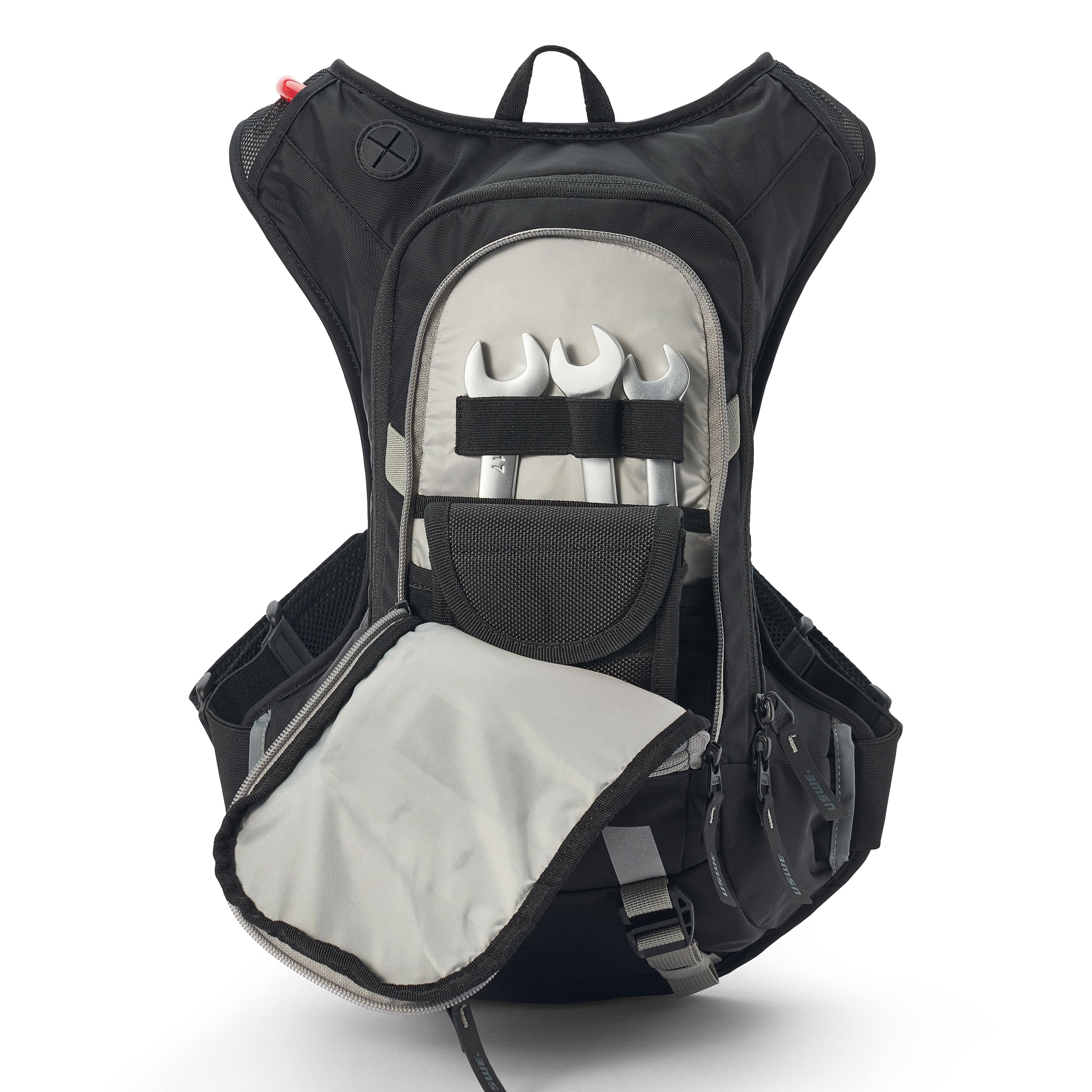 USWE Moto Hydro 12L hydration pack shown with tool compartment open, featuring elastic retention straps securing three wrenches and a mesh pocket, highlighting the pack's organized storage for motorcycle maintenance gear.