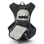 USWE Moto Hydro 8L hydration pack shown with main compartment fully unzipped, exposing tool organizer panel with three wrenches secured by elastic straps, mesh pocket, and gray interior lining, highlighting the pack's internal tool storage and organization features for motorcycle maintenance gear.