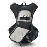 USWE Moto Hydro 8L hydration pack shown with main compartment fully unzipped, exposing tool organizer panel with three wrenches secured by elastic straps, mesh pocket, and gray interior lining, highlighting the pack's internal tool storage and organization features for motorcycle maintenance gear.