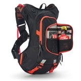 USWE Moto Hydro 8L hydration pack in black with orange trim, front organizer pocket unzipped and extended to show Enervit energy gels and nutrition sachets stored in mesh dividers, with orange waist belt compression straps and reflective gray accents on the harness system.