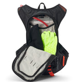 USWE Moto Hydro 8L hydration pack in black with orange mesh shoulder panels, fully opened to reveal 3.0L Elite Hydration Bladder with red hose, neon yellow riding gloves, black mesh bottle holder, and gray interior lining with elastic gear loops for dirt bike storage capacity.