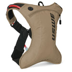 USWE OUTLANDER Moto 2L hydration pack in sand colorway with black vertical logo, showing side profile with adjustable waist strap, red hydration tube, and compact 2L body designed for dirt bike and enduro racing.