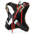 USWE OUTLANDER Moto 2L hydration pack in sand and black colorway, rear three-quarter view highlighting the ventilated mesh back panel, No Dancing Monkey harness buckle system with reflective accents, and red hydration tube with bite valve for motocross riding.