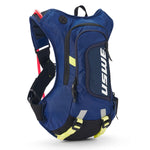 USWE Moto Hydro 8L hydration pack in blue with white USWE branding, featuring black elastic NDM harness straps with red and yellow-green accents, mesh side pocket holding a red tool, dual front zippered compartments, and reflective details on the lower section for off-road motorcycle use.